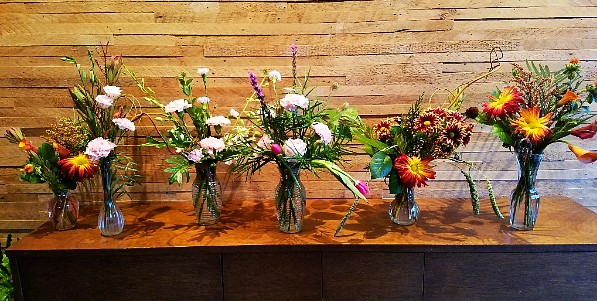 Small bouquets of vibrant flowers being designed for nursing home residents.